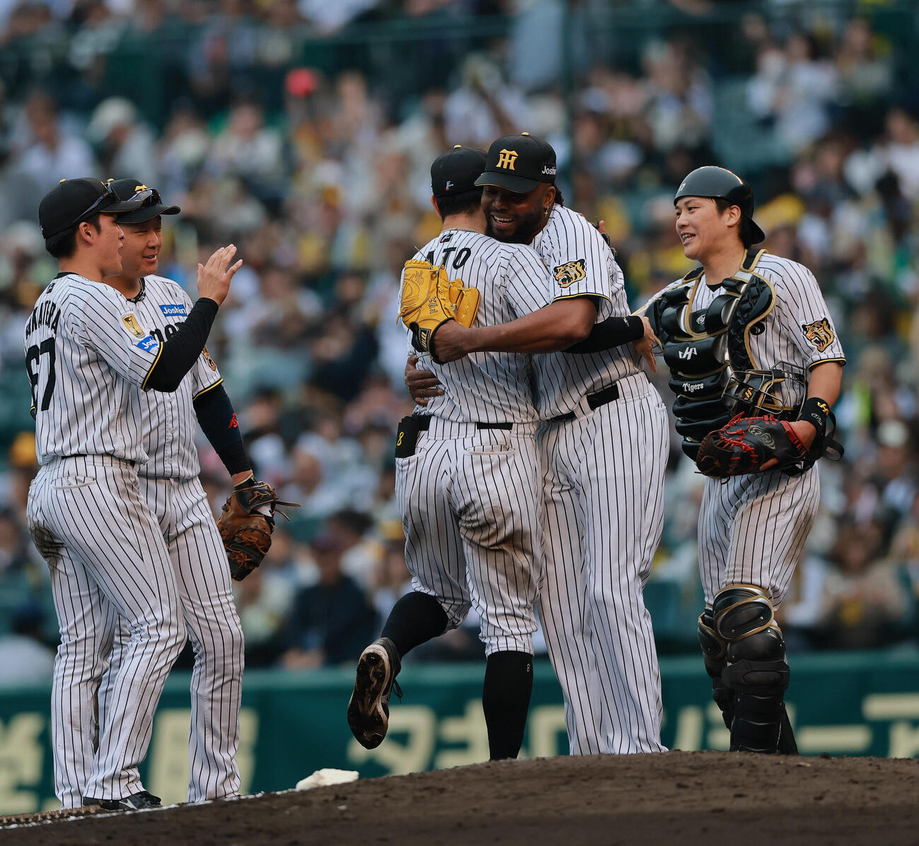 阪神対巨人　巨人に勝利し、試合を締めたラファエル・ドリス（右から2人目）は通算100セーブを達成し、佐藤輝明とハグする（撮影・上山淳一）