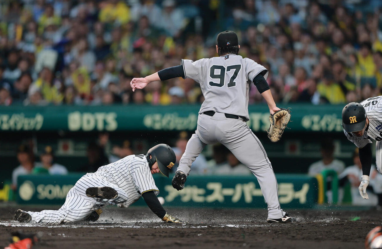 阪神対巨人　6回裏阪神1死満塁、三走中野拓夢（左）は井上温大の暴投で生還する（撮影・上山淳一）