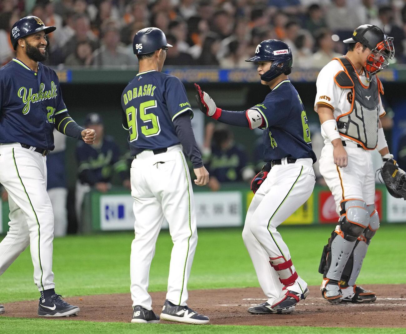3回、先制3ランを放ちコーチ（左から2人目）とタッチを交わすヤクルト・鈴木叶。捕手大城＝東京ドーム