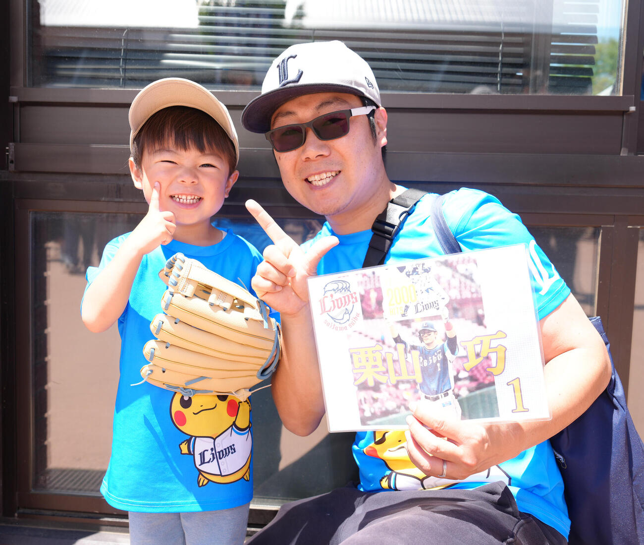 西武対ソフトバンク　小学生以下の来場者に向けた西武西川愛也監修のキッズグローブを受け取り笑顔でポーズを決める親子（撮影・足立雅史）
