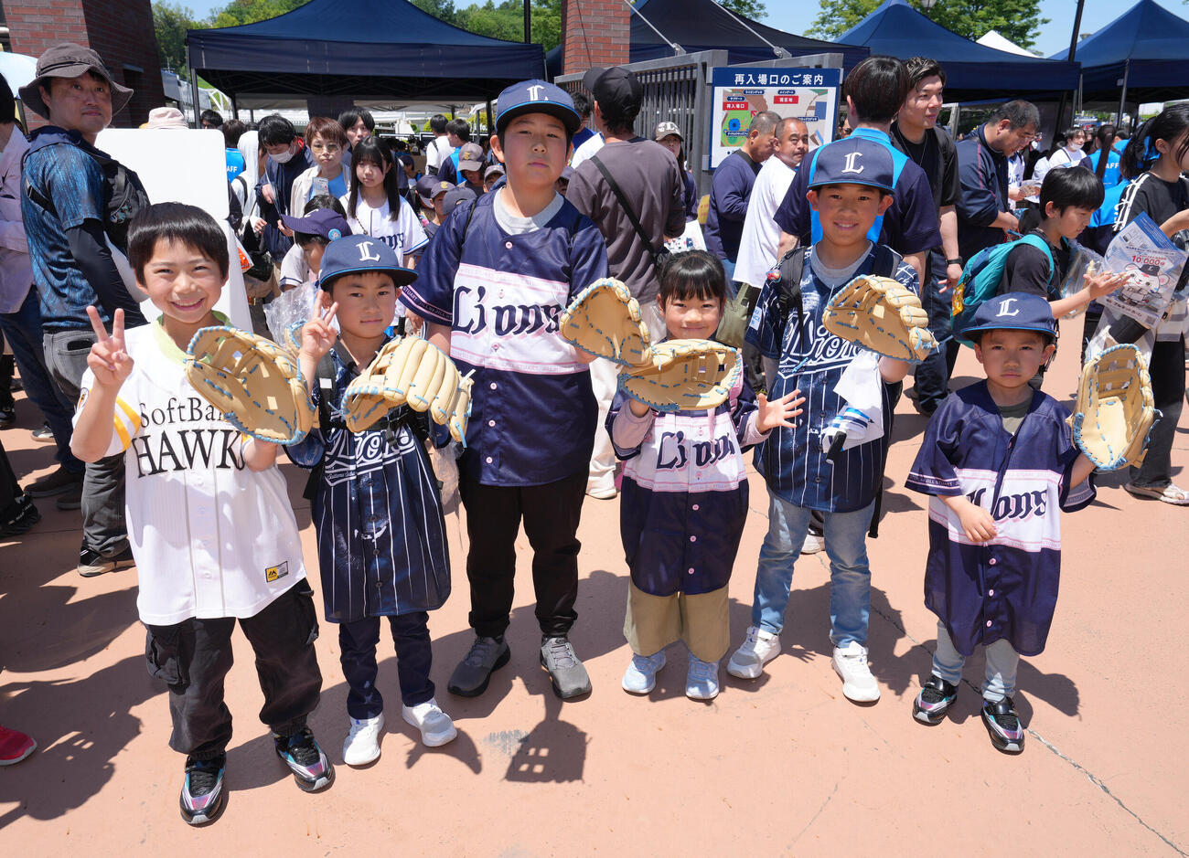 西武対ソフトバンク　小学生以下の来場者に向けた西武西川愛也監修のキッズグローブを受け取り笑顔を見せる子どもたち（撮影・足立雅史）