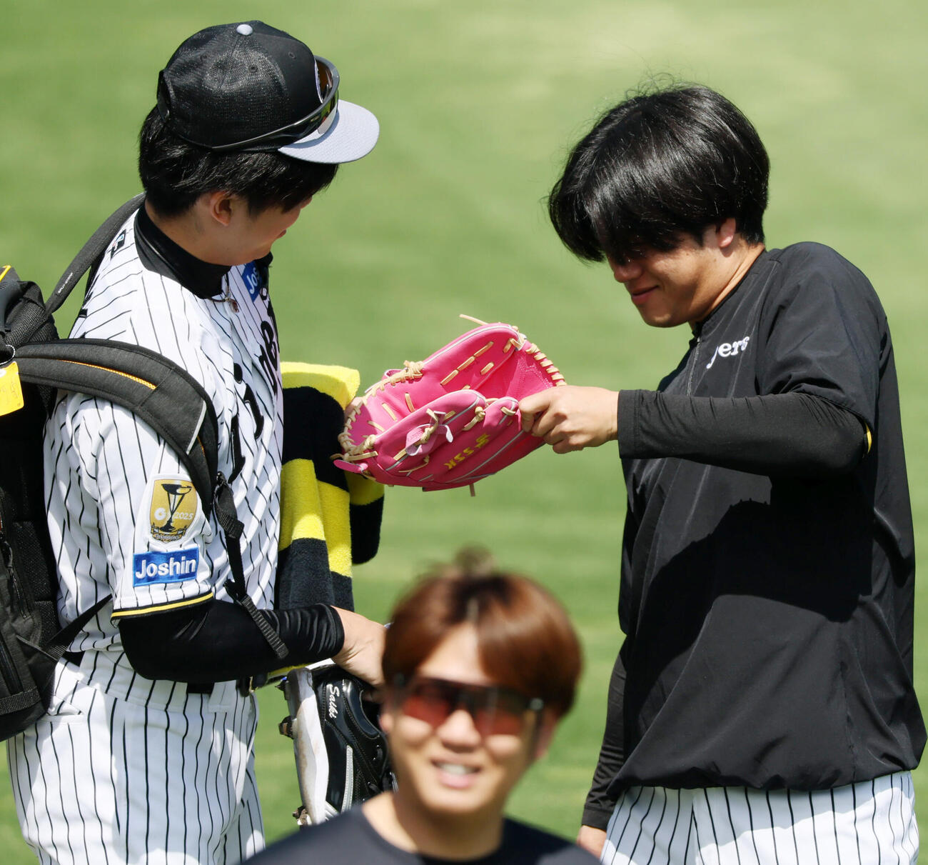 阪神対DeNA　阪神才木浩人（左）の持つピング色のグラブに興味を示す高橋遥人（撮影・加藤哉）