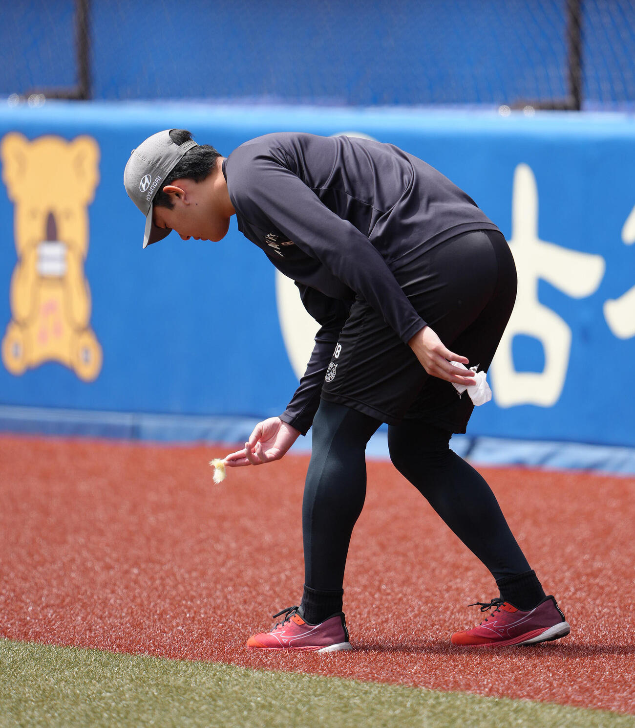 ファーム・リーグ　ロッテ対巨人　試合前、強風でグラウンドに落ちていたゴミを拾うロッテ石垣元気（撮影・足立雅史）