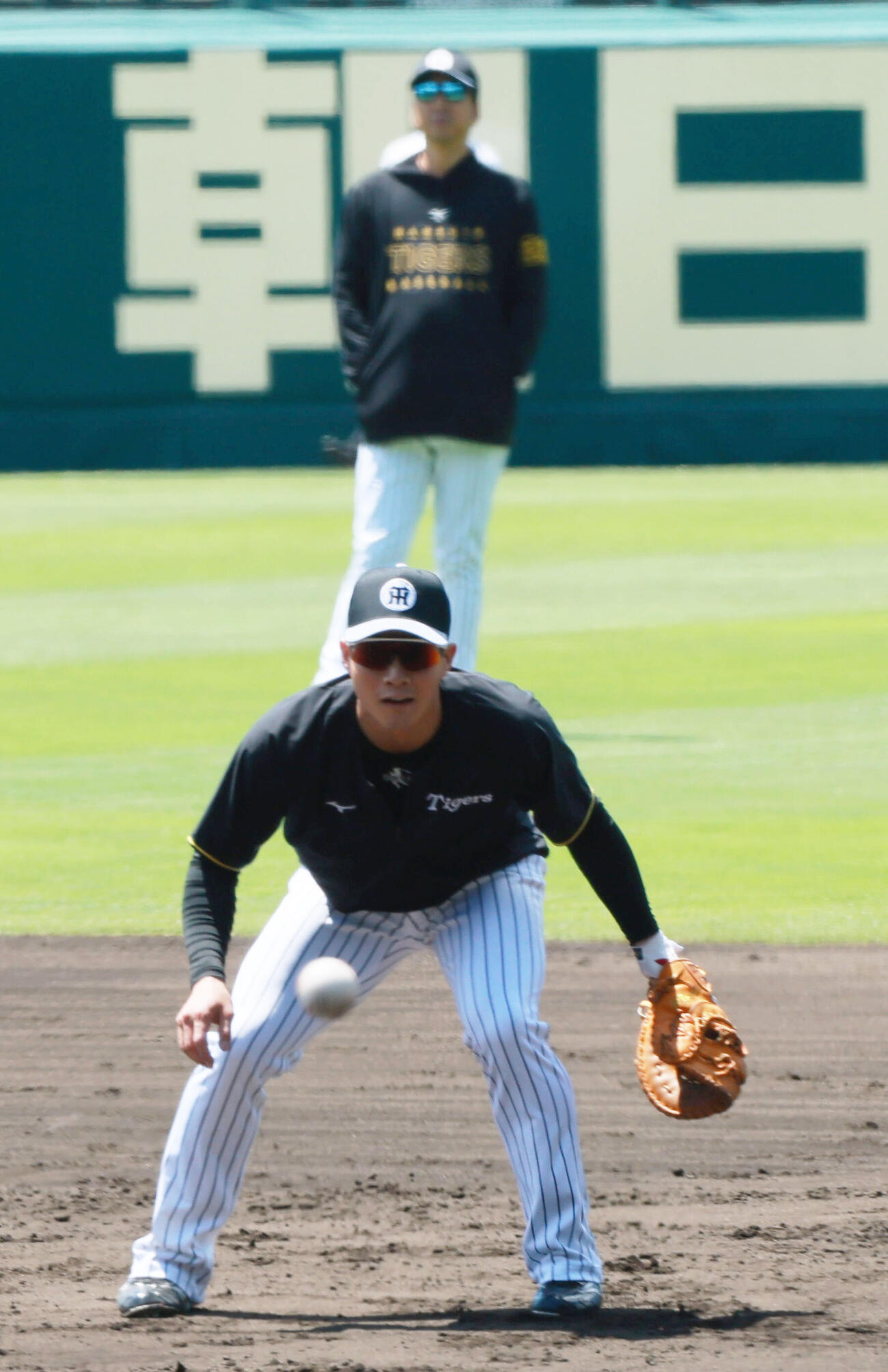阪神対DeNA　試合前の練習で一塁を守る阪神木浪聖也。奥は藤川球児監督（撮影・上山淳一）.