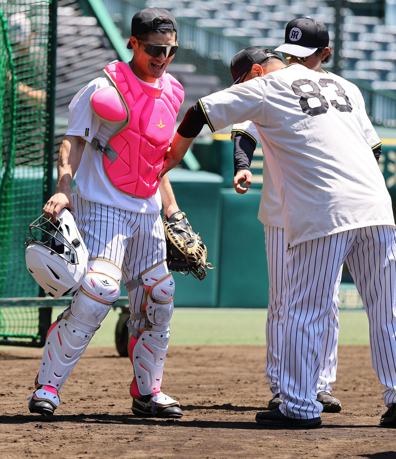 阪神対DeNA　小谷野コーチ（右）にパンチされるもピンクのプロテクターで守られた坂本誠志郎は笑顔を見せる（撮影・上田博志）