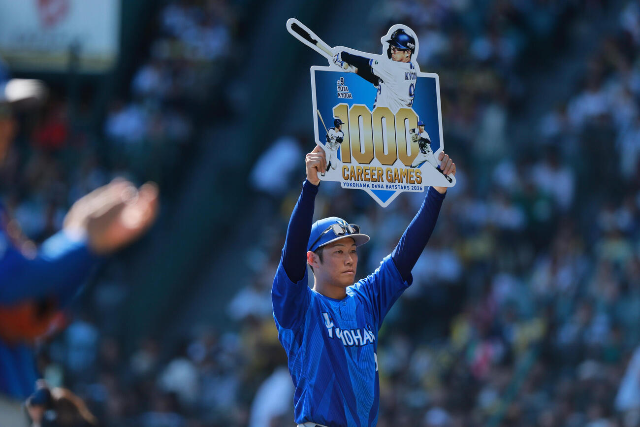 阪神対DeNA DeNA京田陽太はNPB通算1000試合を達成し、記念ボードを掲げる（撮影・上山淳一）