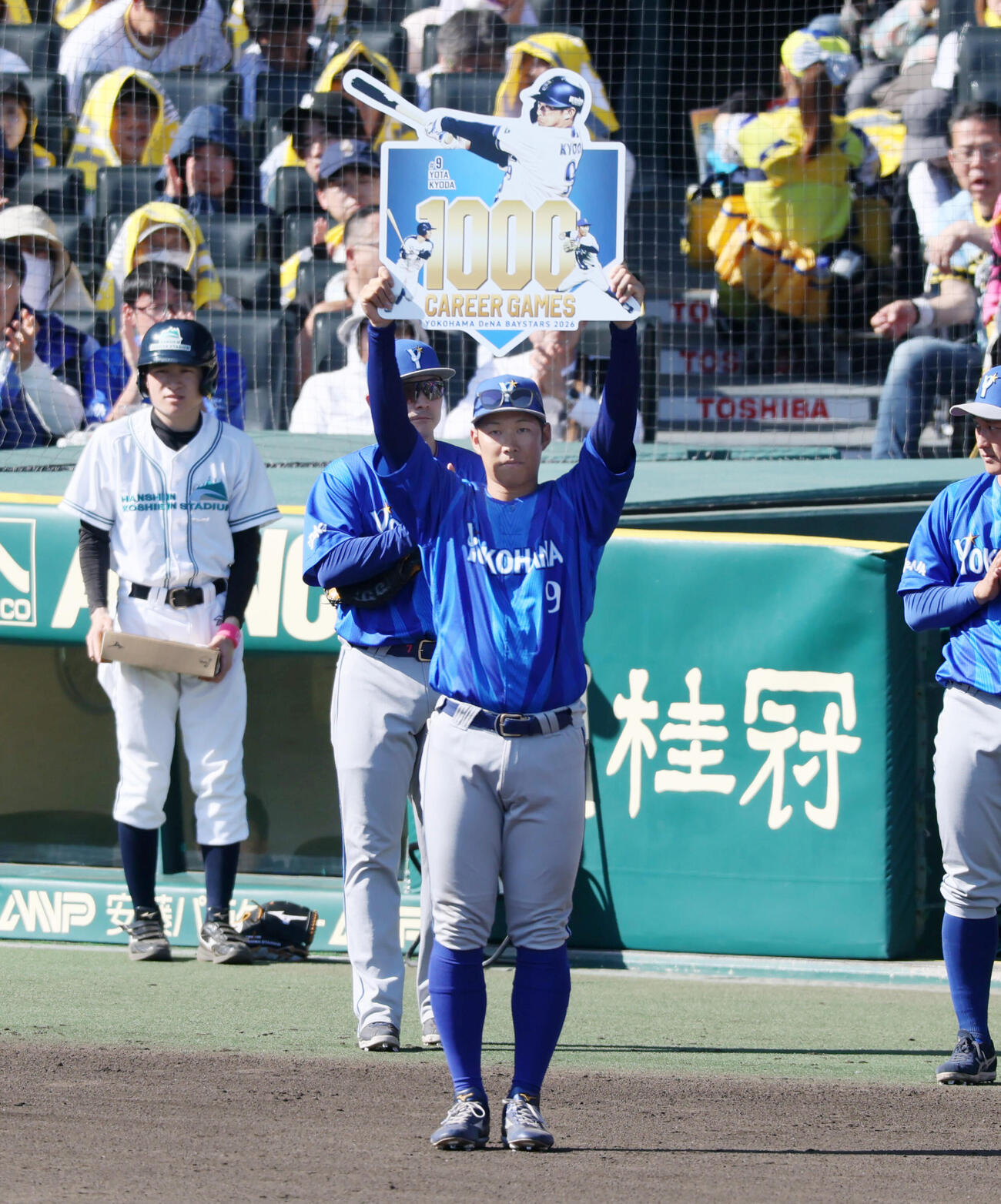 阪神対DeNA 5回裏を終え通算1000試合出場を達成したDeNA京田陽太は記念のボードを手にファンへあいさつする（撮影・加藤哉）