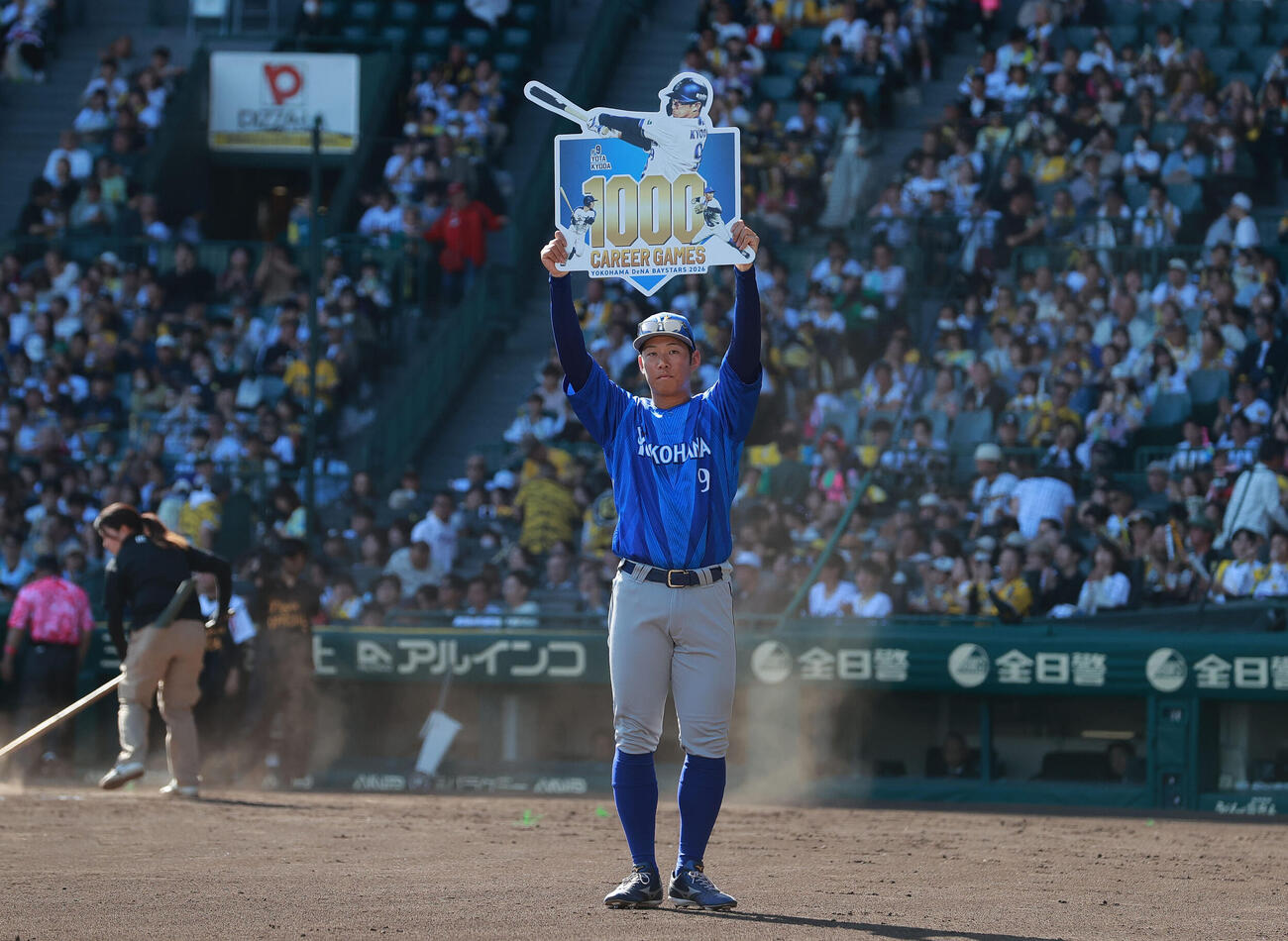 阪神対DeNA DeNA京田陽太はNPB通算1000試合を達成し、記念ボードを掲げる（撮影・上山淳一）