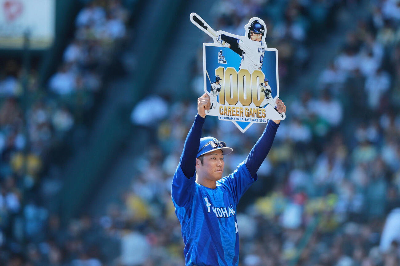 阪神対DeNA DeNA京田陽太はNPB通算1000試合を達成し、記念ボードを掲げる（撮影・上山淳一）