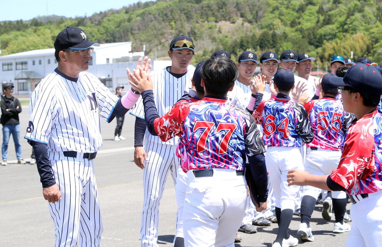 試合後に子供たちとハイタッチする日本製紙石巻・伊藤大造監督(左）