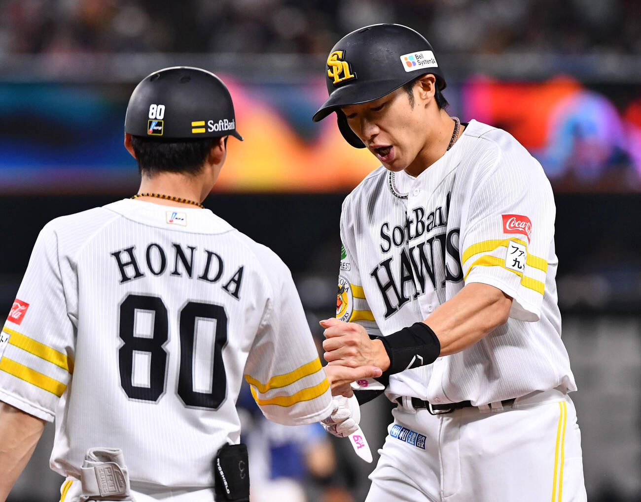 ソフトバンク対西武　3回裏ソフトバンク2死、右前安打で出塁し、本多雄一内野守備走塁兼作戦コーチ（左）とタッチを交わす柳田悠岐（撮影・岩下翔太）