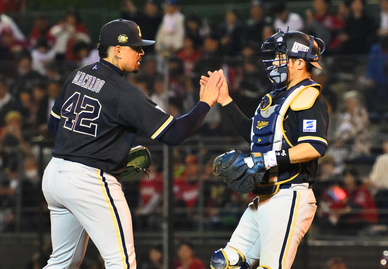 楽天対オリックス　試合を締めたオリックスアンドレス・マチャド（左）は若月健矢とタッチを交わす（撮影・滝沢徹郎）　