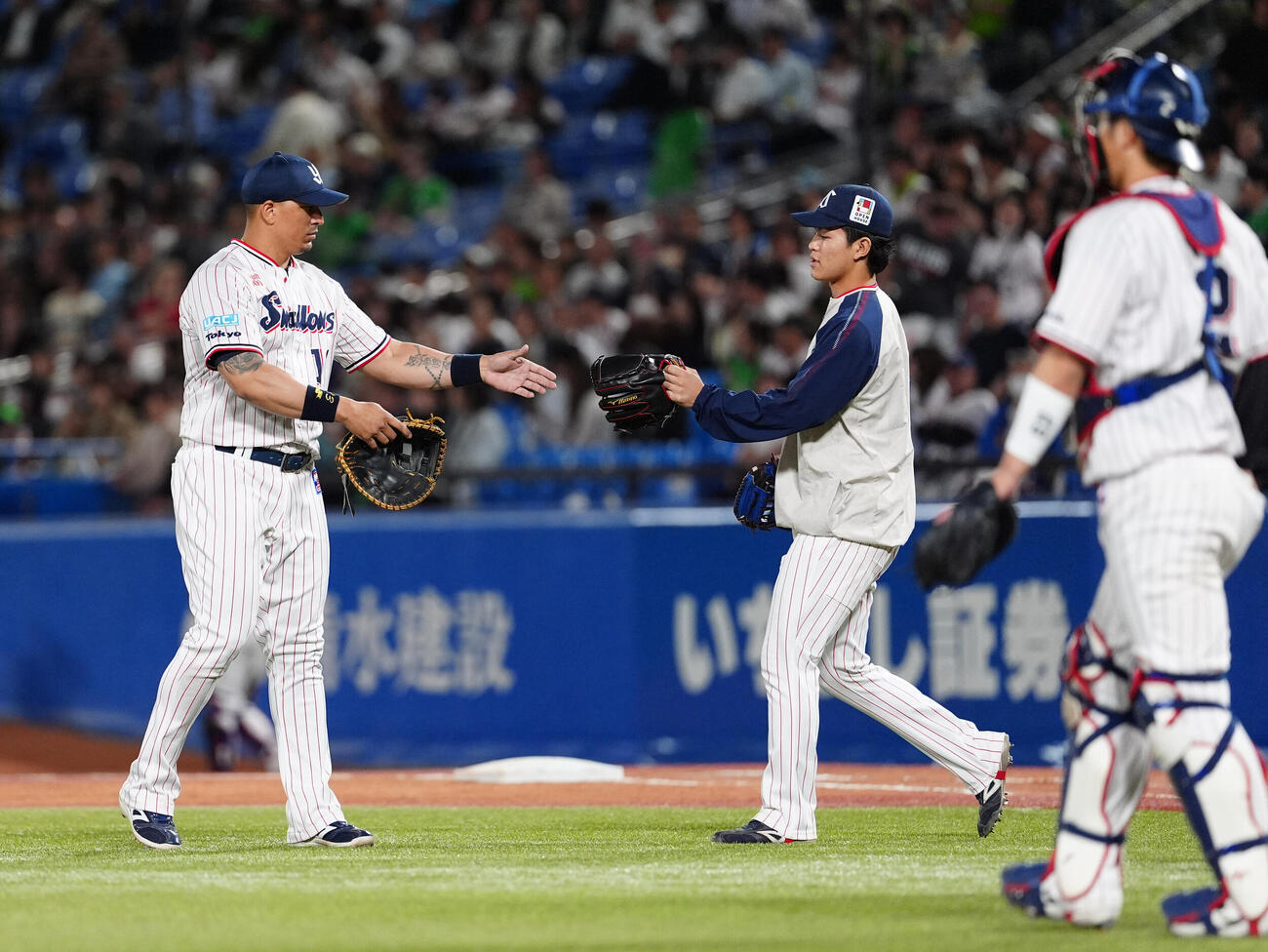 ヤクルト対阪神　9回、大差の展開で登板となったヤクルトのホセ・オスナ（左）はファーストミットからグラブへと交換する（撮影・清水貴仁）
