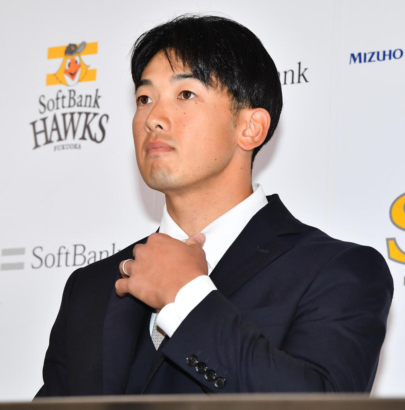 入団会見の席につき、ネクタイを調整するソフトバンク山本祐大（撮影・岩下翔太）
