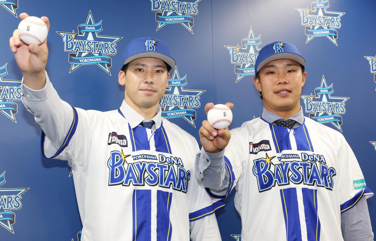 ソフトバンクからトレードでDeNAに入団し、笑顔でボールを握る尾形崇斗（左）と井上朋也（撮影・宮地輝）