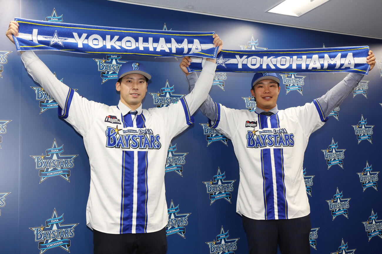 ソフトバンクからトレードでDeNAに入団し、笑顔でタオルを掲げる尾形崇斗（左）と井上朋也（撮影・宮地輝）