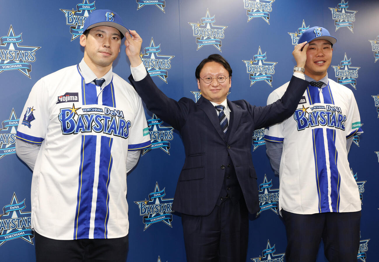 ソフトバンクからトレードでDeNAに入団し、木村洋太球団社長（中央）から帽子をかぶせてもらう尾形崇斗（左）と井上朋也（撮影・宮地輝）
