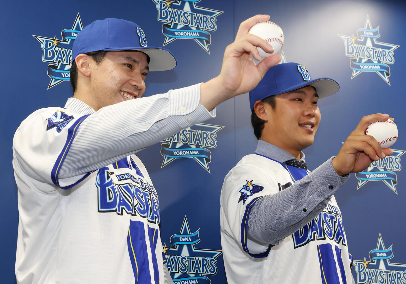 ソフトバンクからトレードでDeNAに入団し、笑顔でボールを握る尾形崇斗（左）と井上朋也（撮影・宮地輝）