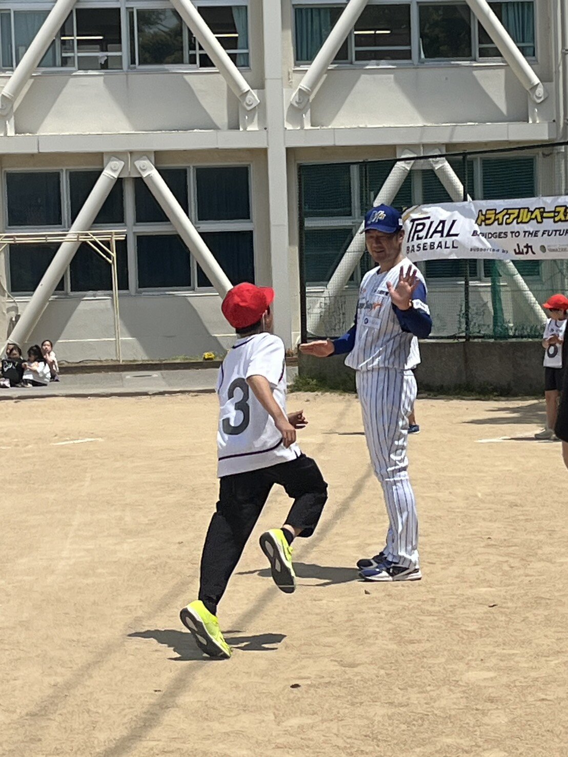 トライアルベースボールに参加し、児童とハイタッチする日本海L石川の岡崎監督（撮影・村松万里子）