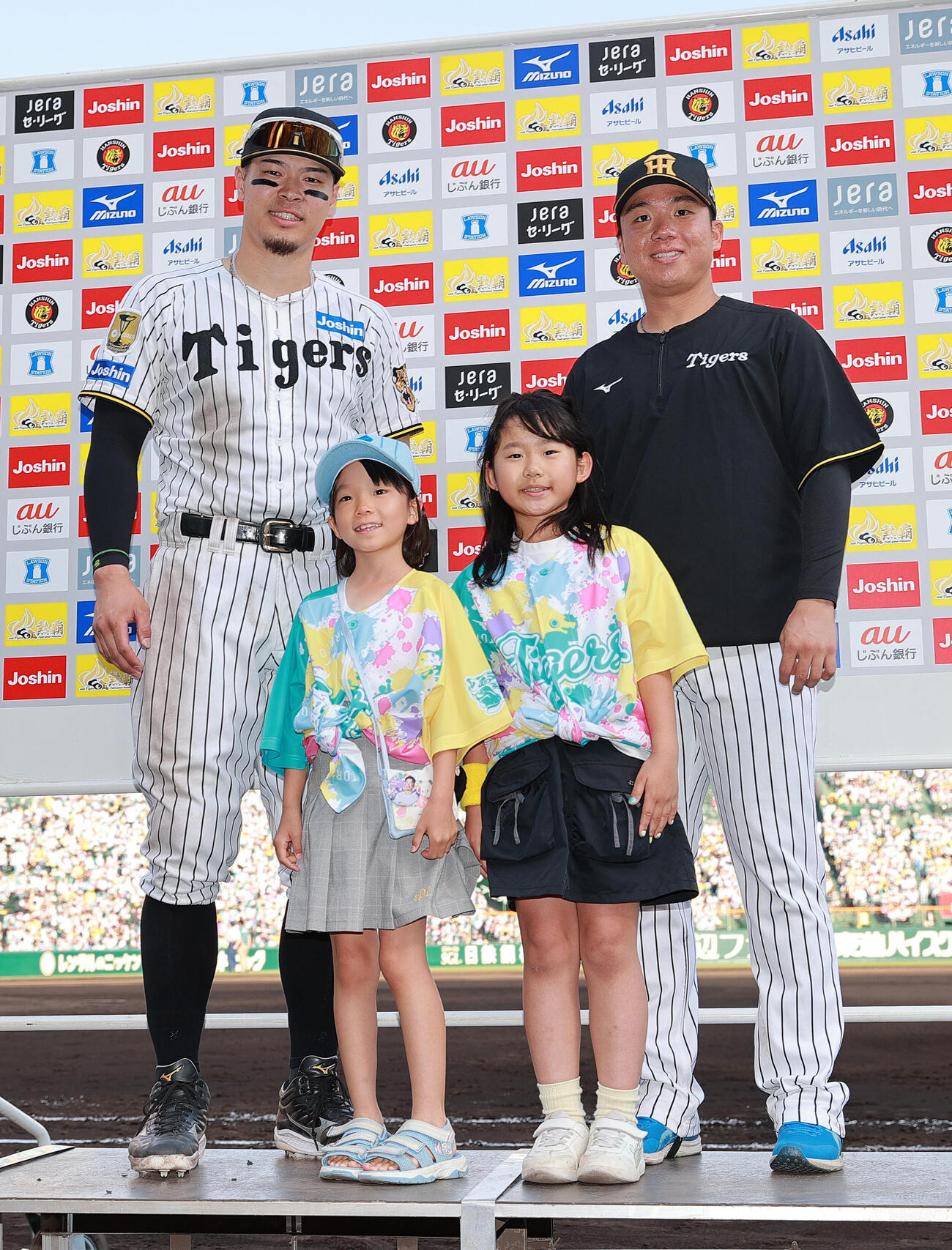 阪神対広島　ヒーローの阪神佐藤輝明（左）と村上頌樹はTORACO DAYで選ばれた児童と記念撮影する（撮影・上山淳一）