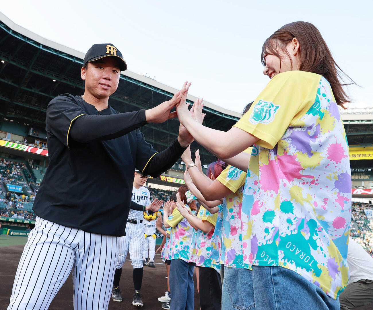 阪神対広島　ヒーローの阪神村上頌樹はTORACO DAYで選ばれたファンとタッチかわす（撮影・上山淳一）
