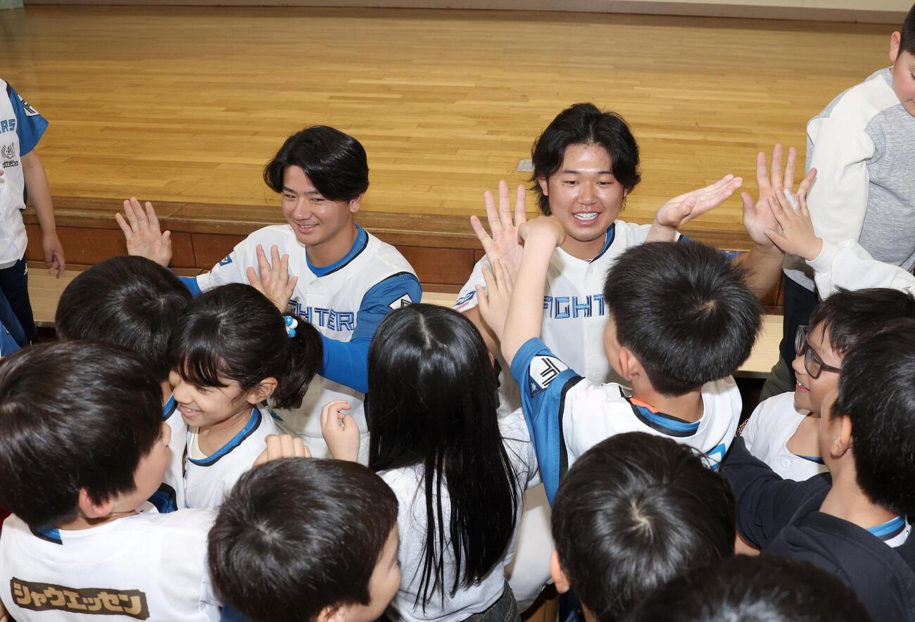 北広島市内の小学校で児童とハイタッチする大塚瑠晏（左）と進藤勇也（撮影・黒川智章）