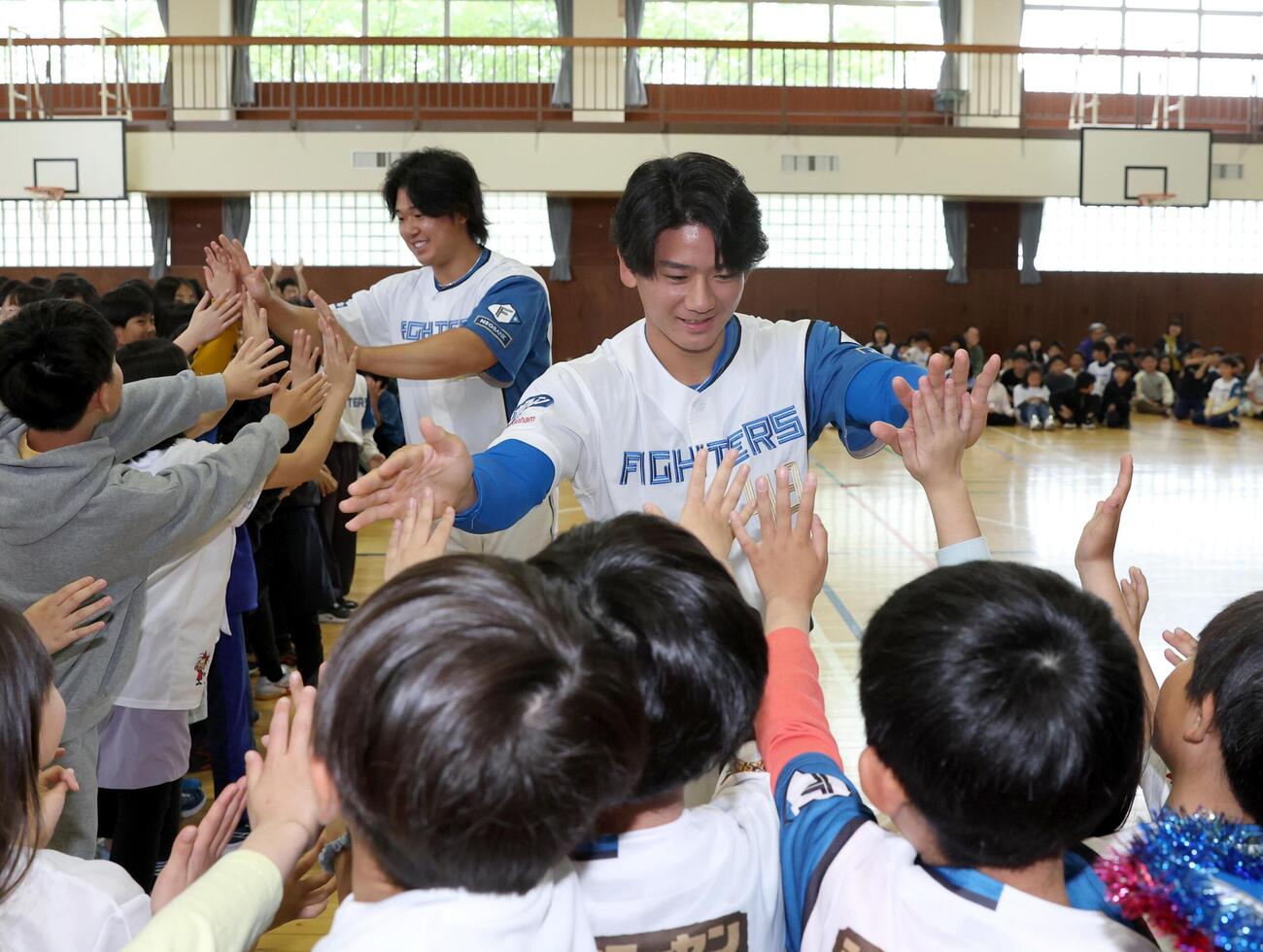 北広島市内の小学校で児童とハイタッチする大塚瑠晏（右）と進藤勇也（撮影・黒川智章）