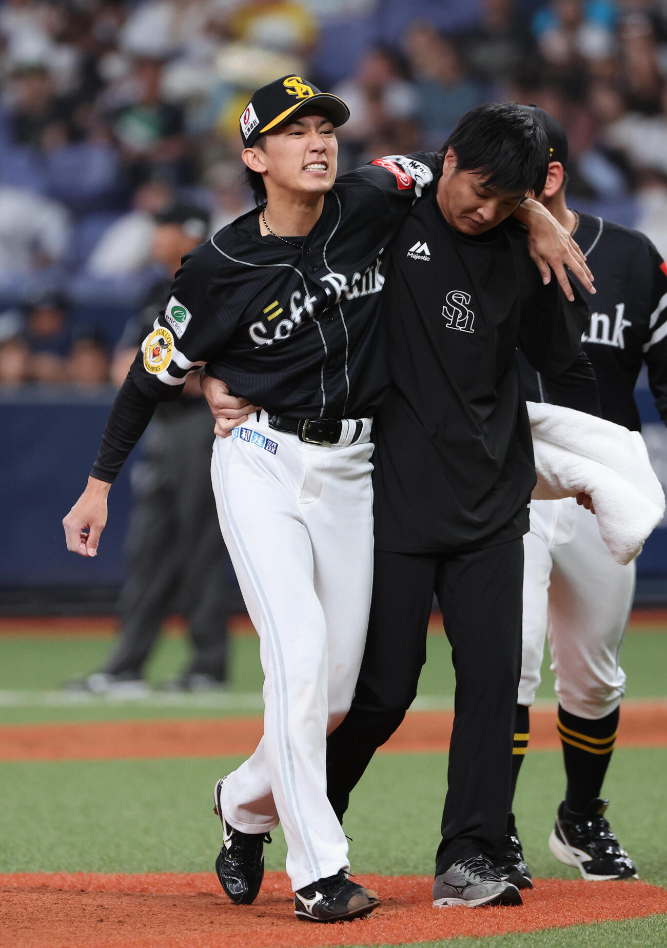 オリックス対ソフトバンク　2回裏オリックス2死、若月の打球が当たったソフトバンク大津亮介は肩を借りて治療のためベンチに戻る（撮影・西尾就之）