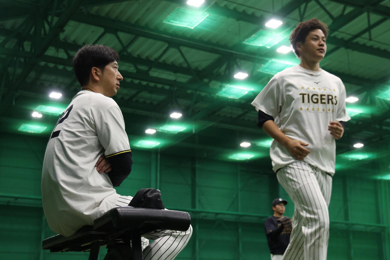 阪神対中日　室内練習場で練習を見守る阪神藤川球児監督（左）。右はウオーミングアップを行う大竹耕太郎（撮影・前田充）