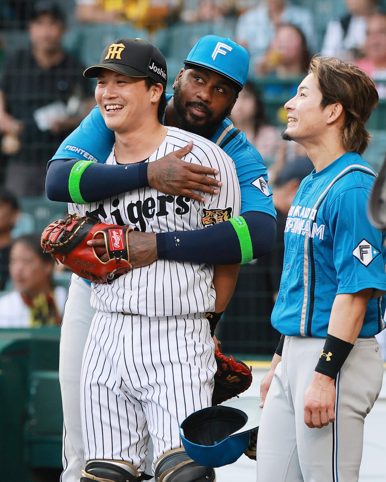 セ・パ交流戦　阪神対日本ハム1回戦　阪神対日本ハム　試合前、阪神伏見寅威（左）に抱きつく日本ハムフランミル・レイエス（中央）（撮影・上山淳一）＝2026年5月26日..
