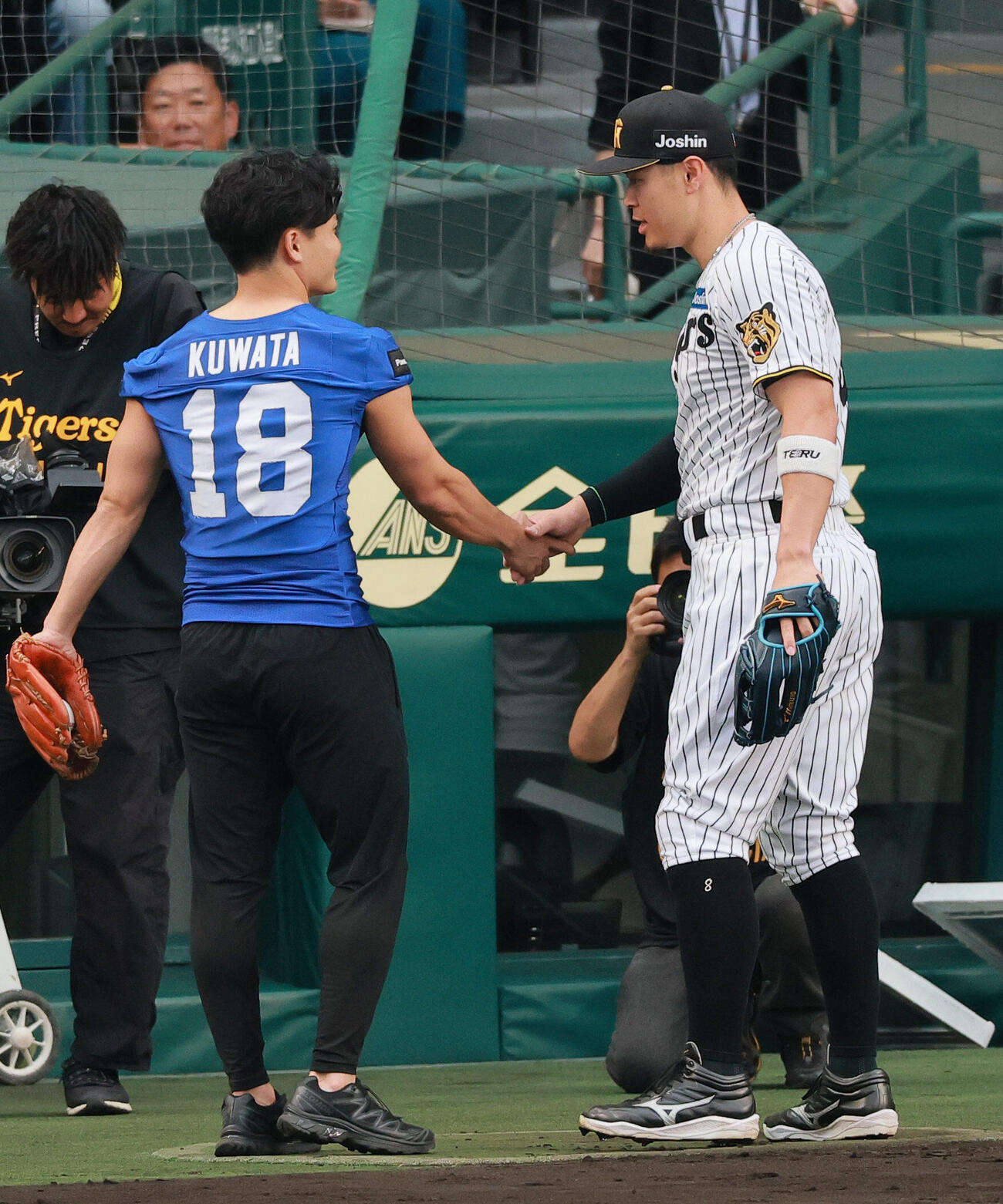 セ・パ交流戦　阪神対日本ハム2回戦　阪神対日本ハム　ファーストピッチを終えたアメリカンフットボール・パナソニックインパルスの桑田理介（左）と握手をかわす阪神佐藤輝明（撮影・上山淳一）＝2026年5月27日