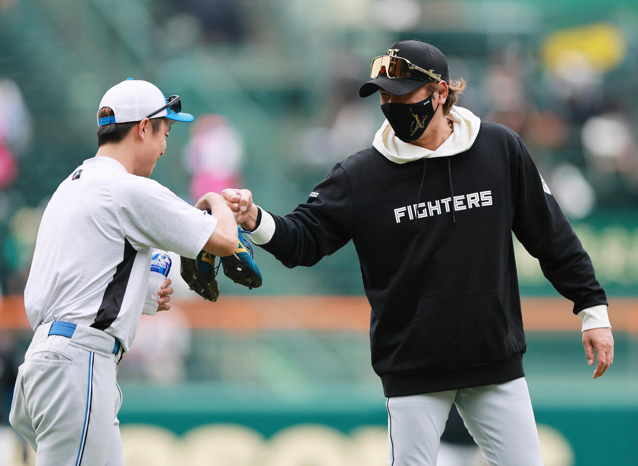 阪神対日本ハム　試合前の練習で日本ハム島本浩也（左）とグータッチする新庄剛志監督（撮影・上山淳一）