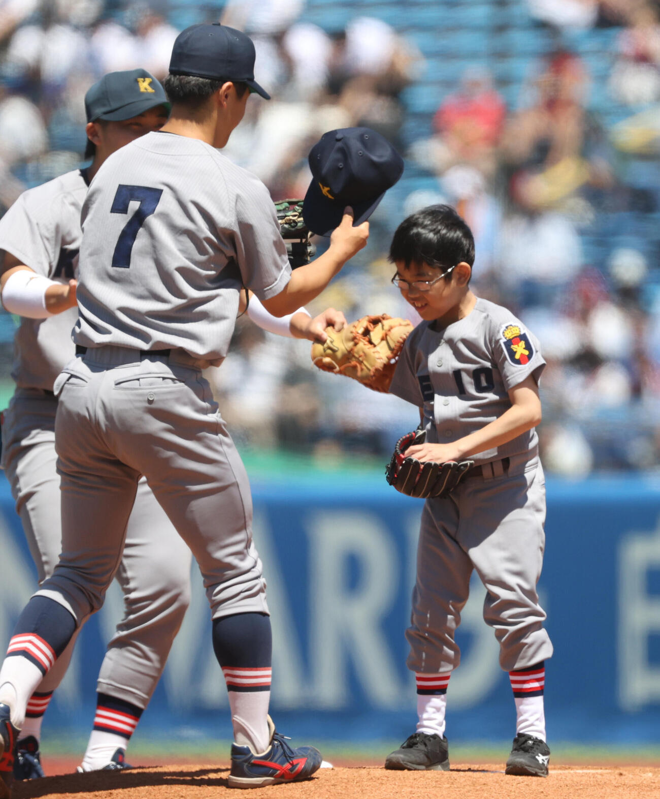 6大学野球　早大対慶大戦で始球式を務めた慶大野球部の草間実月君（右）は帽子を飛ばされ林純司からかぶせてもらう（撮影・柴田隆二）