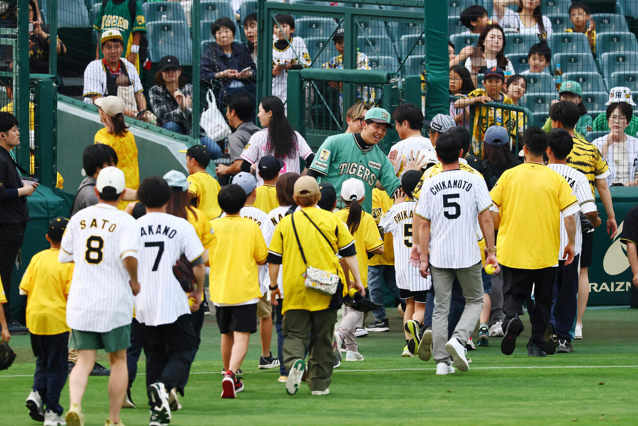 阪神対楽天　グラウンドで親子によるキャッチボールイベントが行われ参加者とタッチする阪神才木浩人（撮影・加藤哉）