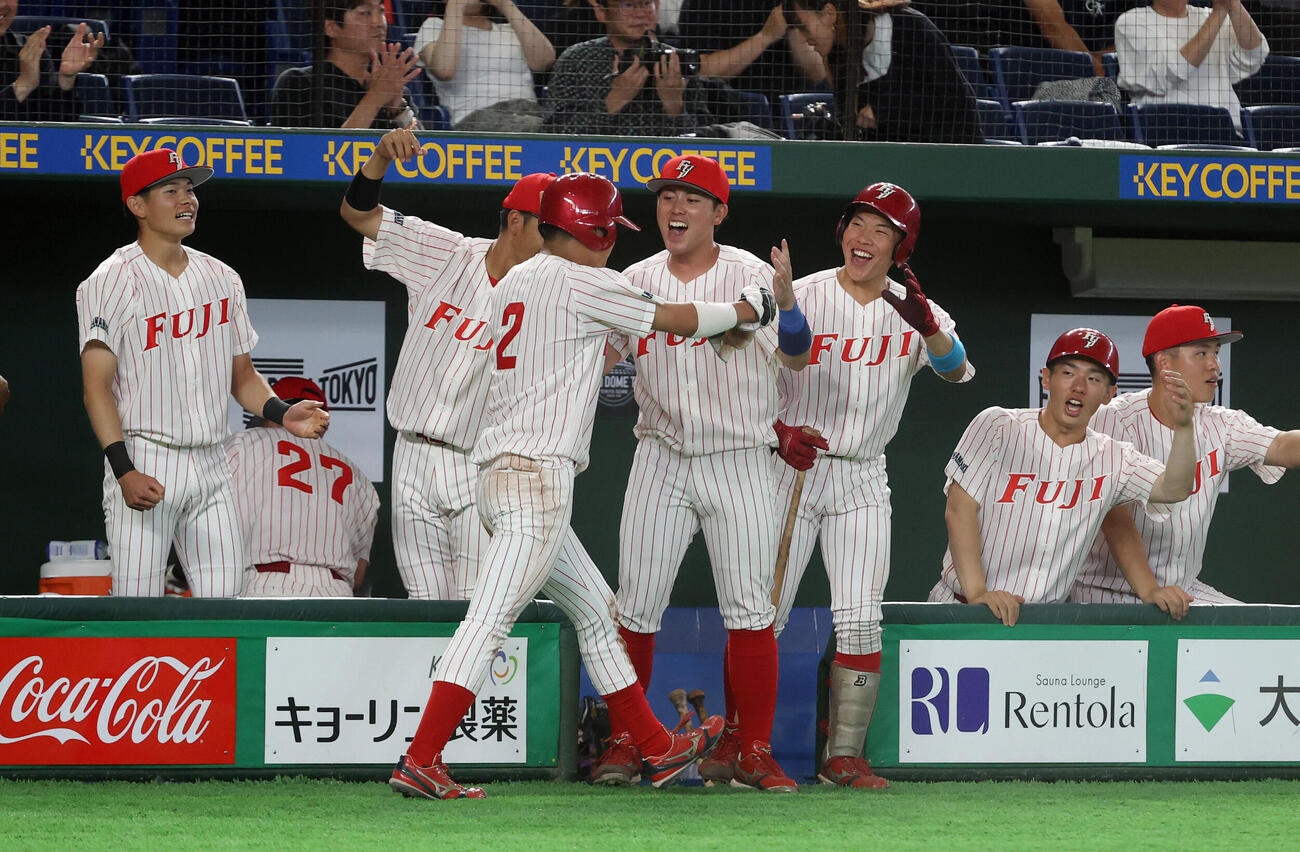 東海大九州対富士大　5回裏富士大1死三塁、梅村団の打球が三塁手の野選になり三塁走者松谷徹平が生還しナインの出迎えを受ける（撮影・柴田隆二）