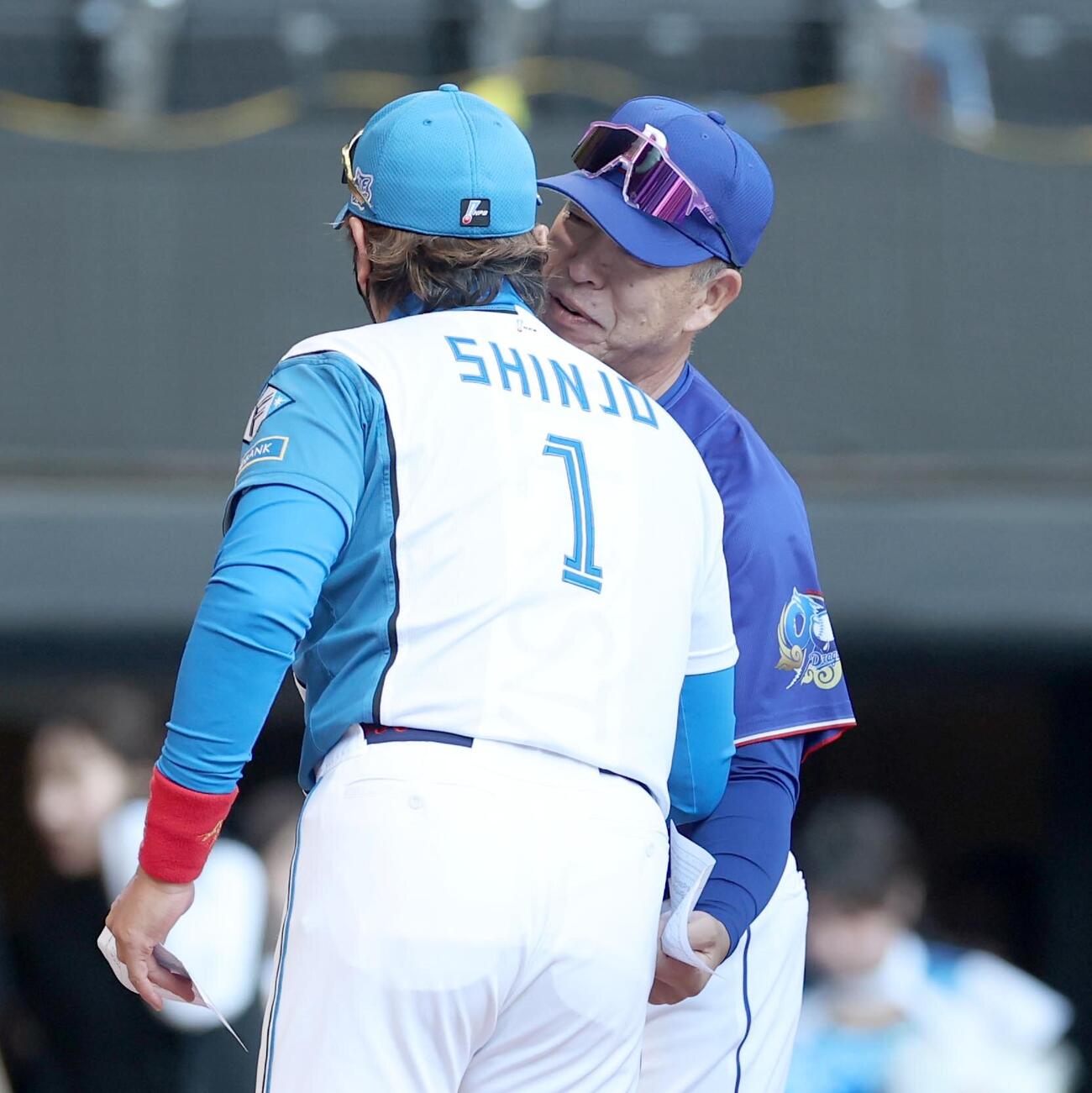 日本ハム対中日　メンバー表交換で新庄剛志監督の耳元で何かをささやく井上一樹監督（撮影・黒川智章）