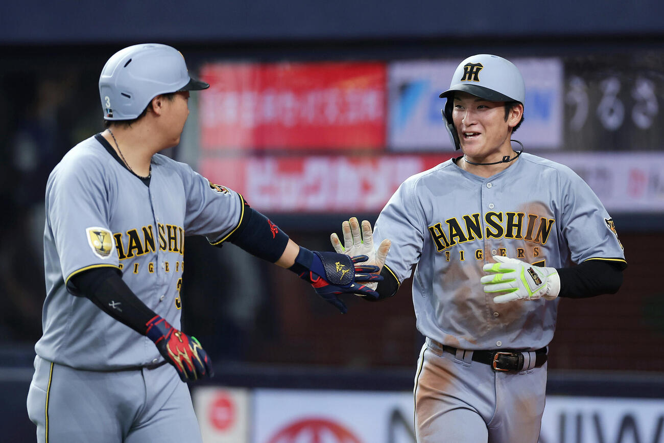 オリックス対阪神　3回表阪神1死満塁、佐藤輝明（の犠飛で生還し大山悠輔（左）とタッチを交わす高寺望夢撮影・前田充）