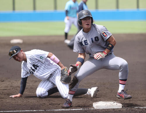 3回表A組2死一塁、神奈川大・神田剛志の右前安打で一塁走者の慶大・今津慶介(左)が三塁を陥れる、相手のエラーで生還する。左は亜大・山里宝三塁手(撮影・柴田隆二)