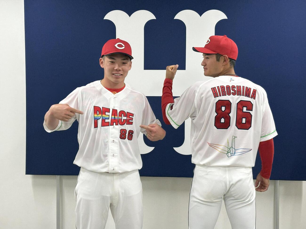 8月6日「ピースナイター」で着用する特別ユニホームを着用した広島持丸泰輝捕手（写真左）と名原典彦外野手（同右）