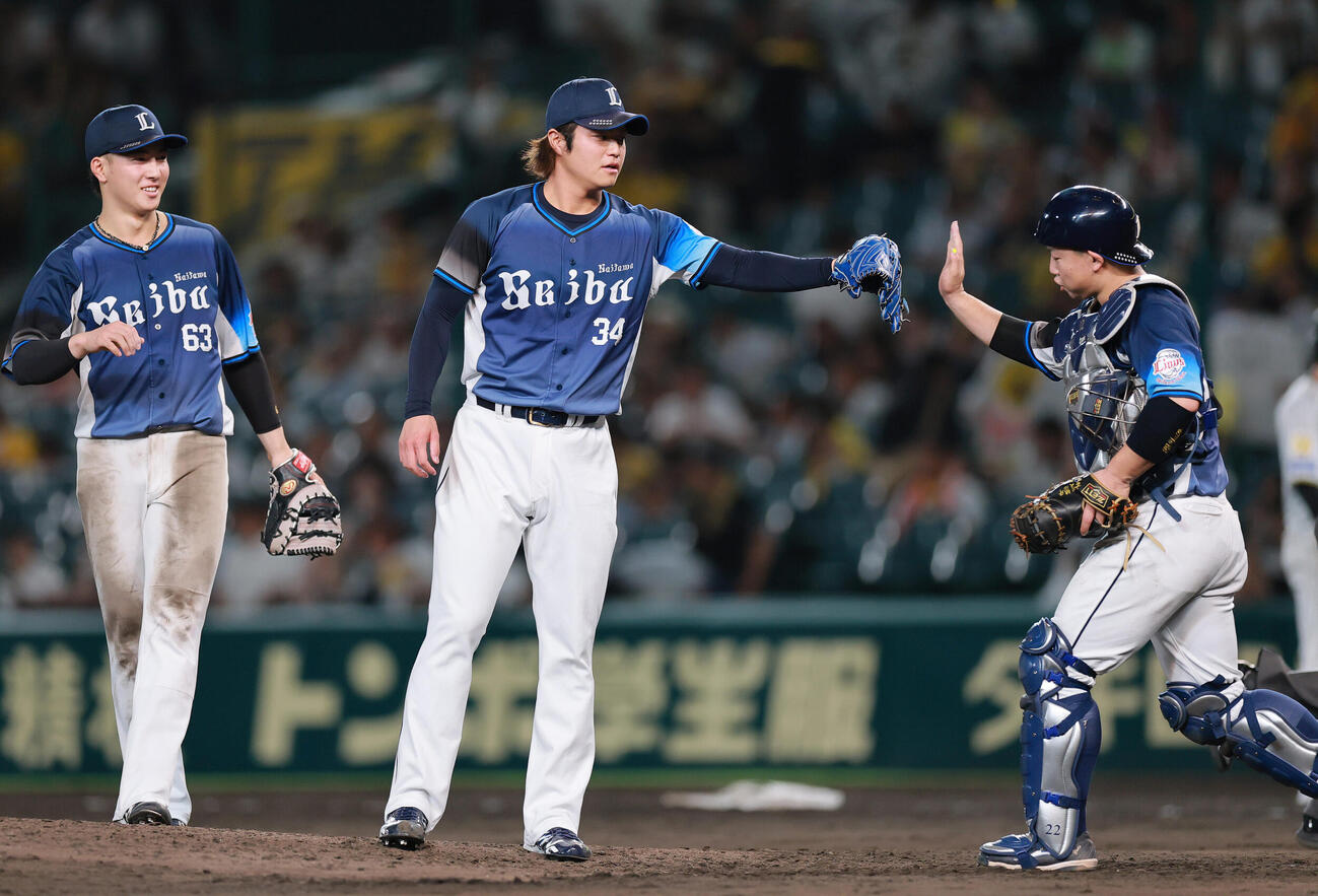阪神対西武　阪神に勝利し、試合を締めた甲斐野央（中央）は捕手居古賀悠斗とタッチをかわす（撮影・上山淳一）