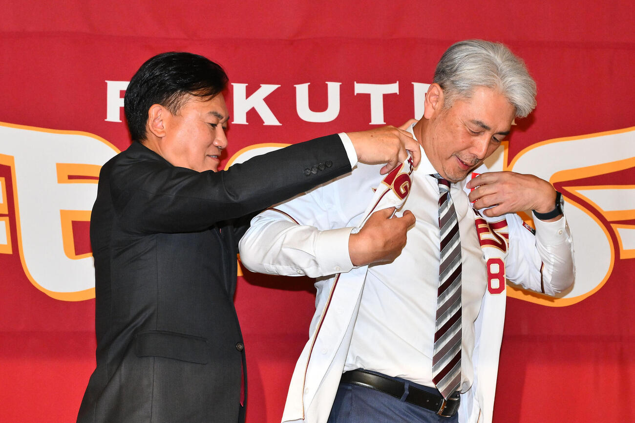 楽天吉井理人新監督（右）は三木谷浩史オーナーからユニホームを着させてもらう（撮影・滝沢徹郎）