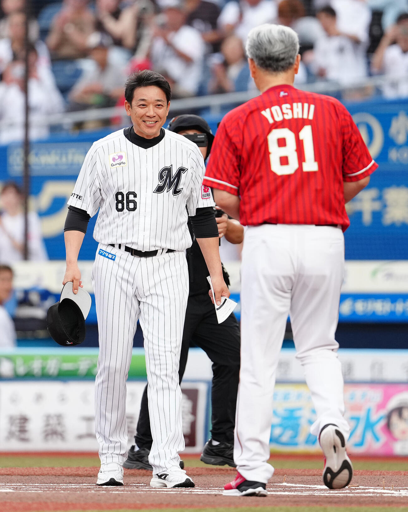 ロッテ対楽天　楽天吉井理人監督（手前）とのメンバー表の最終確認に笑顔で向かうロッテのサブロー監督（撮影・鈴木みどり）