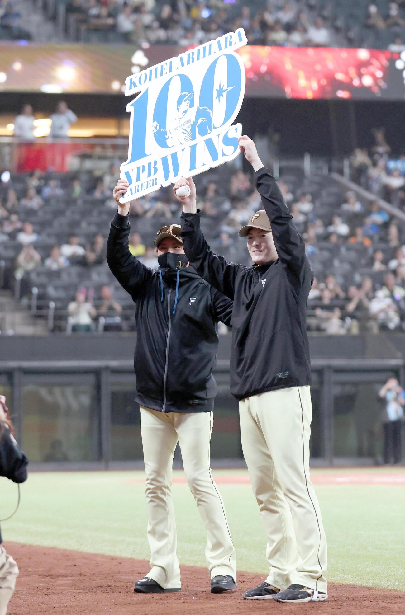 日本ハム対オリックス　NPB通算100勝を達成し記念ボードを新庄剛志監督（左）と掲げる有原航平（撮影・黒川智章）