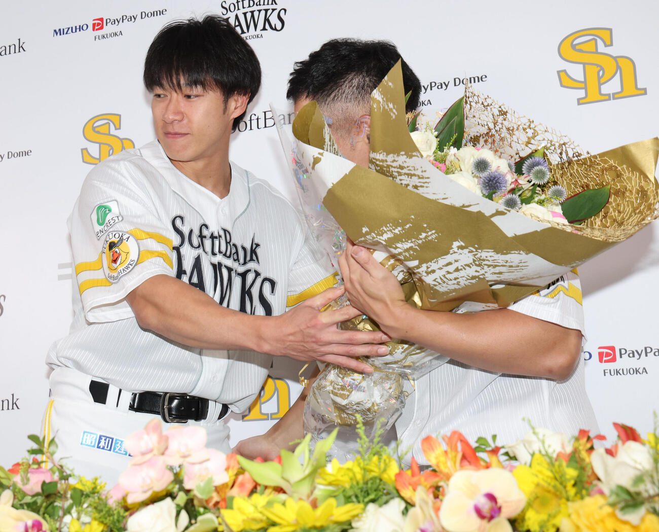 引退会見を終えたソフトバンク中村晃は柳田悠岐から花束を贈られる（撮影・梅根麻紀）