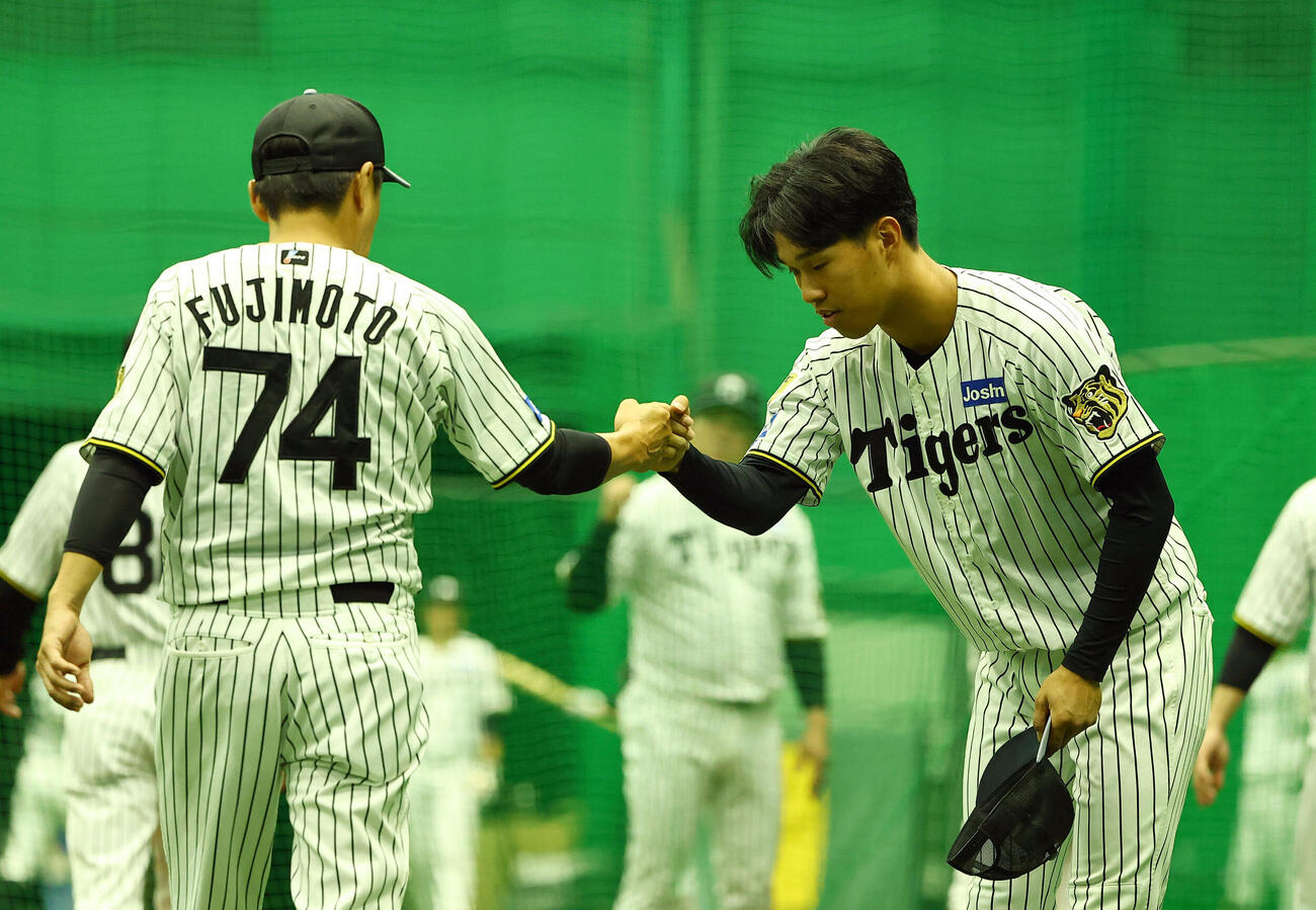 1軍に合流した阪神岡城快生（右）は藤本敦士コーチとグータッチする（撮影・上田博志）