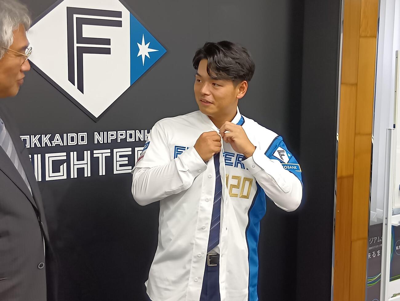 入団会見に臨んだ日本ハムの日渡騰輝捕手。左は日本ハムの木田GM代行（撮影・沢田啓太郎）