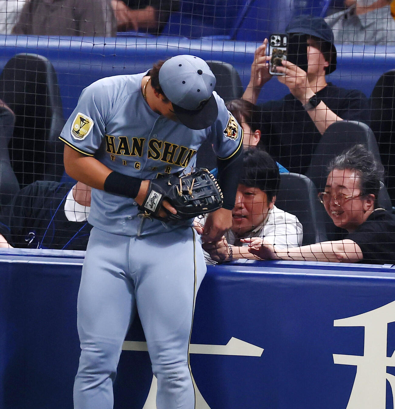 中日対阪神　8回裏中日1死、前川右京は尾田剛樹の邪飛を追ってスタンドのネットに身体がはまったはずみでポケットのボタンが絡み、お客さんの手助けではずしてもらう（撮影・加藤哉）