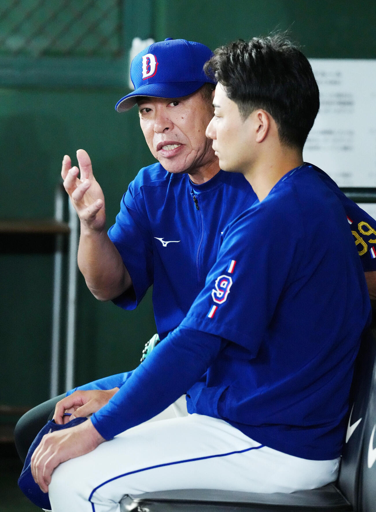巨人対中日　試合前練習中、ベンチで中日石伊雄太（手前）と話す井上一樹監督（撮影・江口和貴）