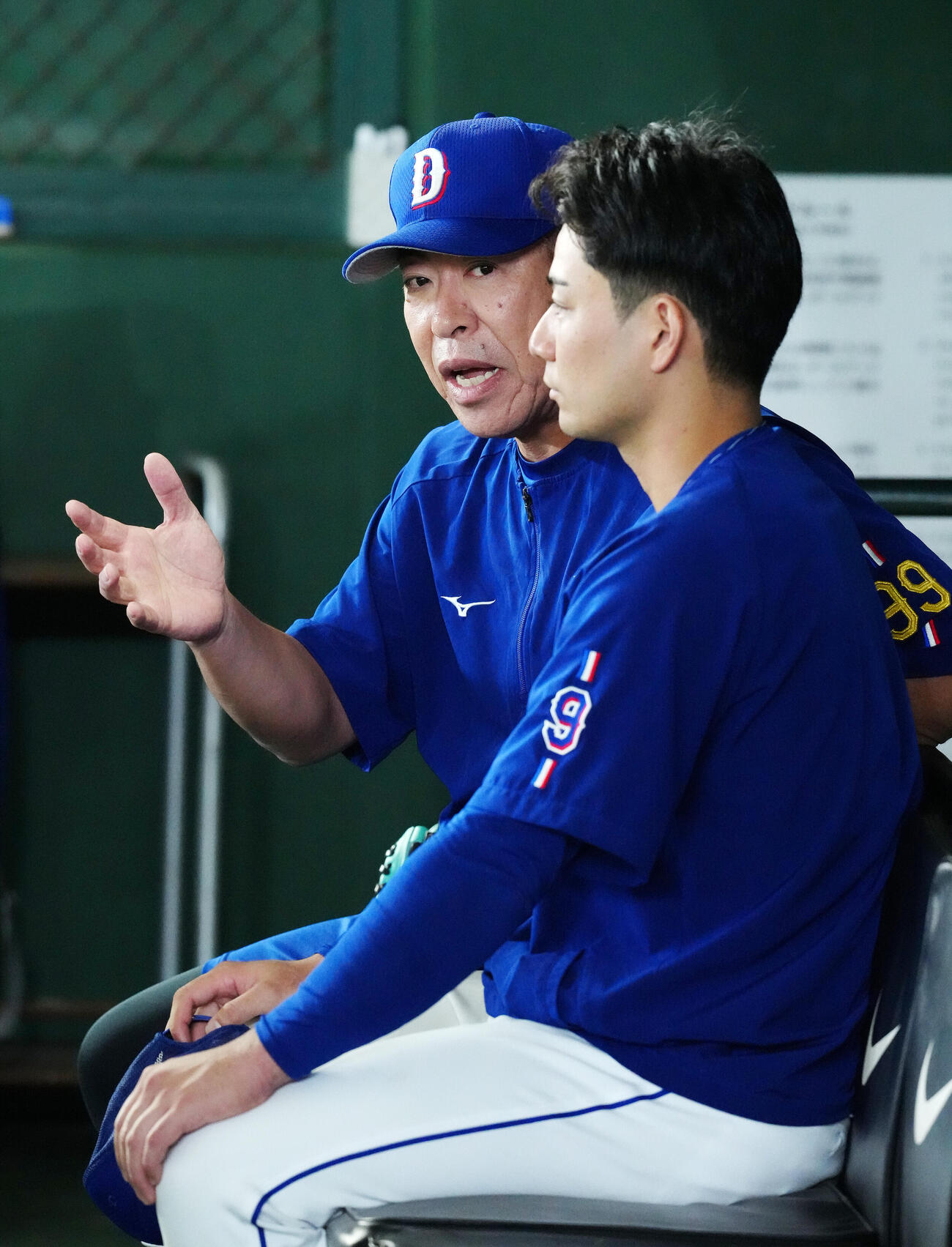 巨人対中日　試合前練習中、ベンチで中日石伊雄太（手前）と話す井上一樹監督（撮影・江口和貴）