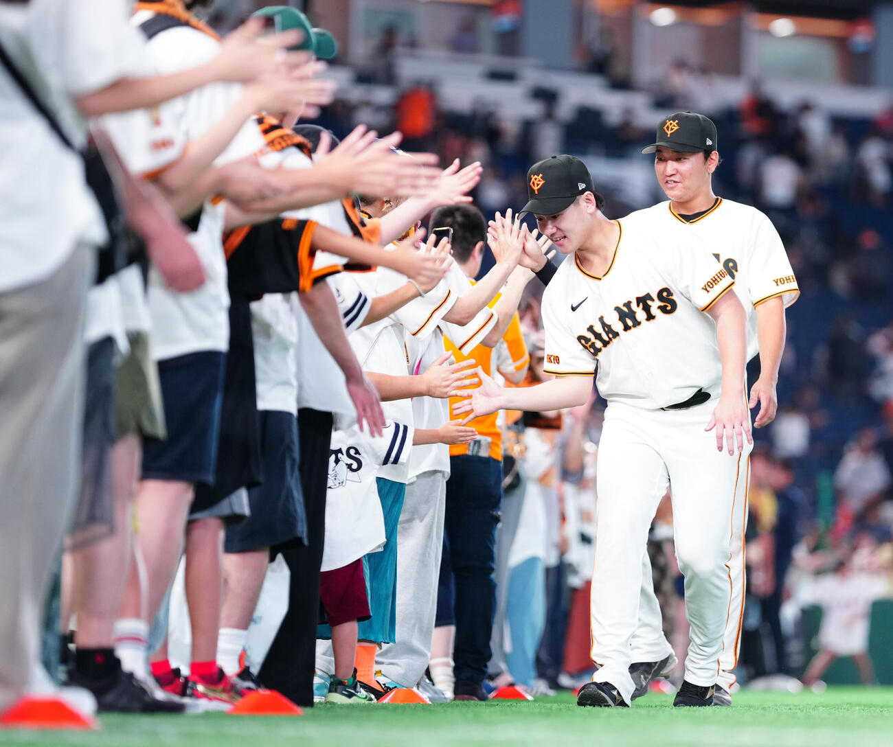 巨人対広島　広島に勝利し、ファンとハイタッチする巨人井上温大と笹原操希（右）（撮影・鈴木みどり）